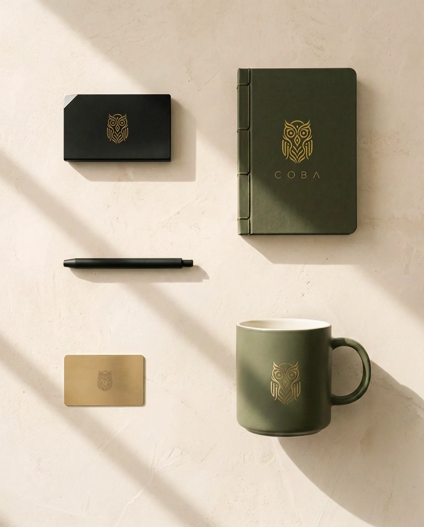The COBA membership kit — brass-foil keycard, olive notebook, black card wallet and a sage mug on lime plaster.
