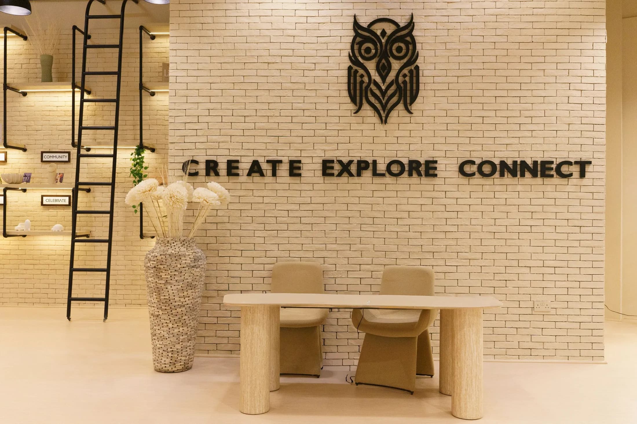The COBA owl mark and the words Create Explore Connect in black lettering on the white brick wall of the main hall.
